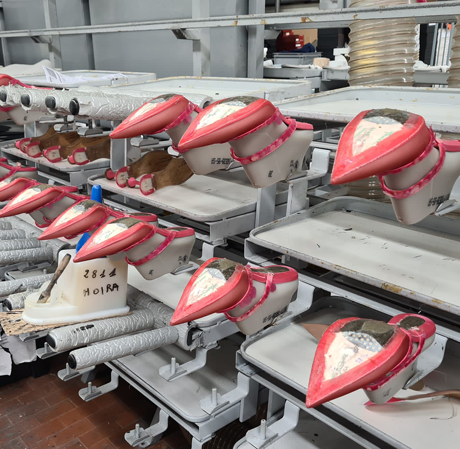 This image features Britt Netta's Margot Mule in her production facility in Italy. Margot mules sit upon a last in a row waiting to have the soles applied to them