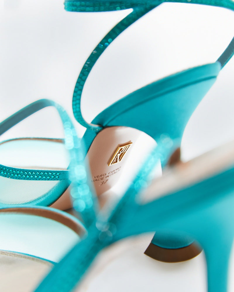 
                  
                    Creative view of Dani Lace up. TEAL SATIN LACE-UP WITH CRYSTAL EMBELLISHMENT  Hand-crafted in Italy, the Dani (“Dani”) lace-up features a glossy teal satin and is set upon our custom 95mm heel designed for your comfort. Dani is accented with our signature mesh upper that gently molds to your foot and is adorned with rows of glistening crystals that wrap around your foot and leg for an irresistible touch of sparkle.
                  
                